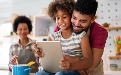 Family in kitchen with kid on tablet