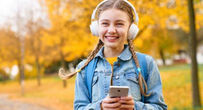 Girl walking outside listening to music on mobile device