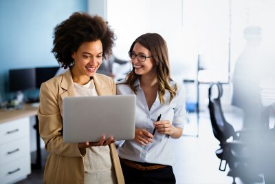 Women working in a corporate office looking at a laptop and talking