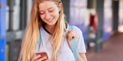 Young teen girl in school looking at cellphone